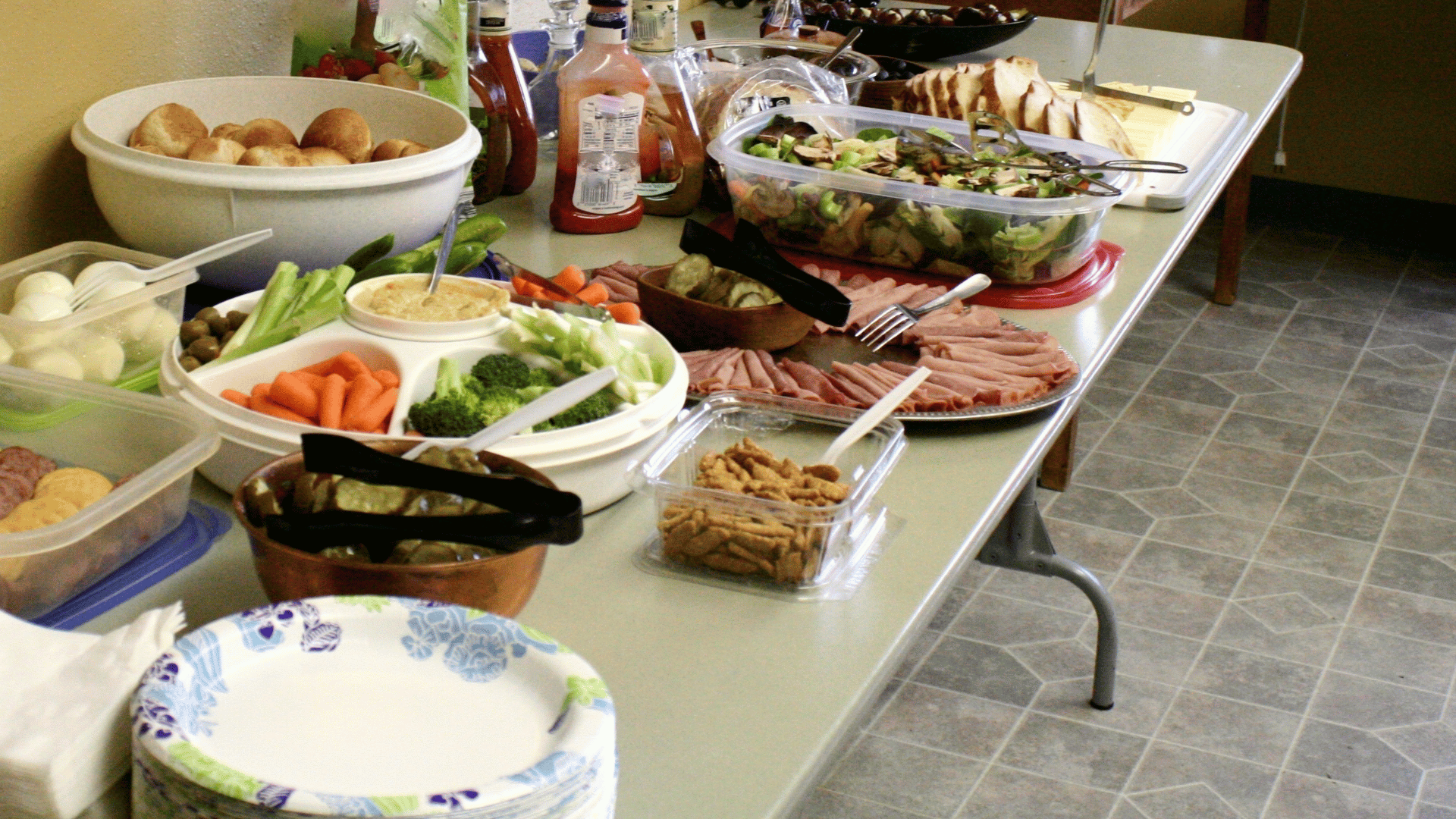 A colorful potluck table with labeled dishes and coordinated serving utensils planned in Mealmento