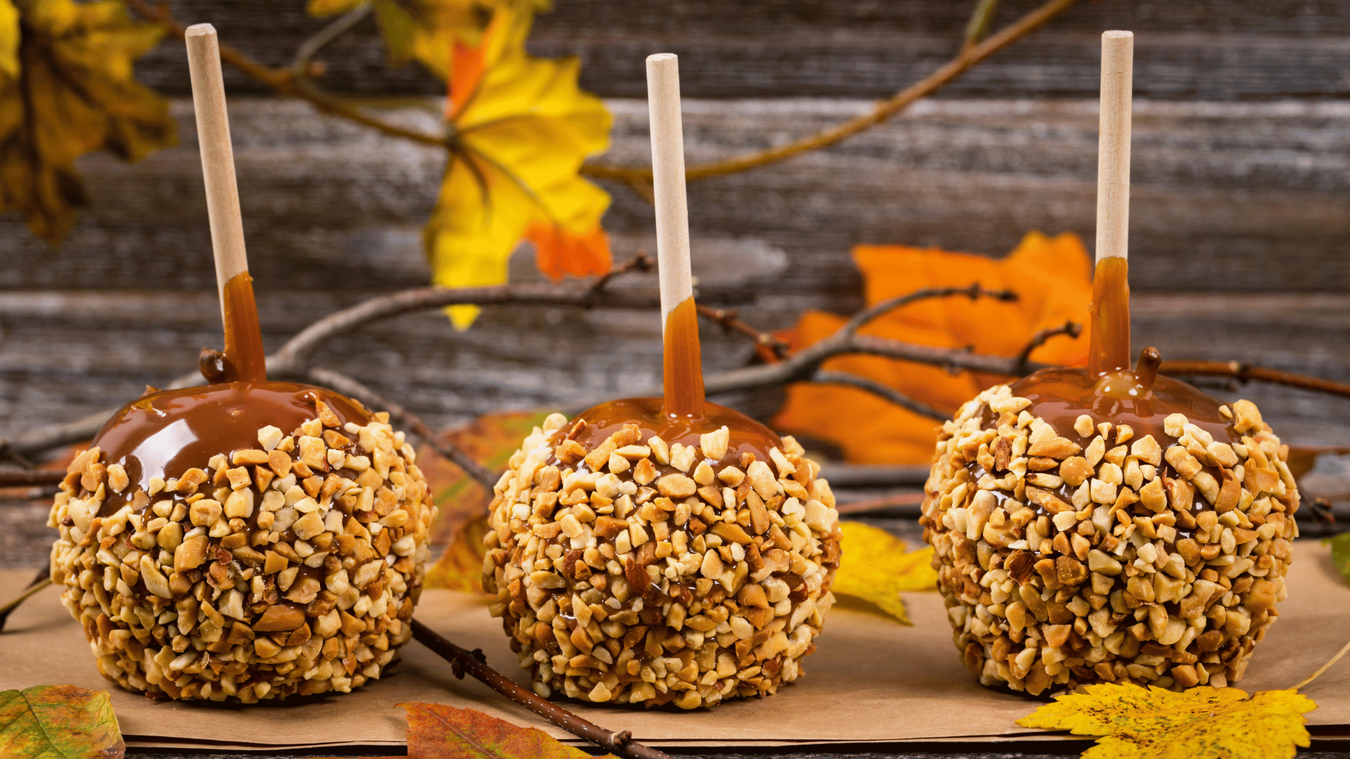 Caramel apples, popcorn balls, and ghost cookies displayed on a Halloween table with Mealmento