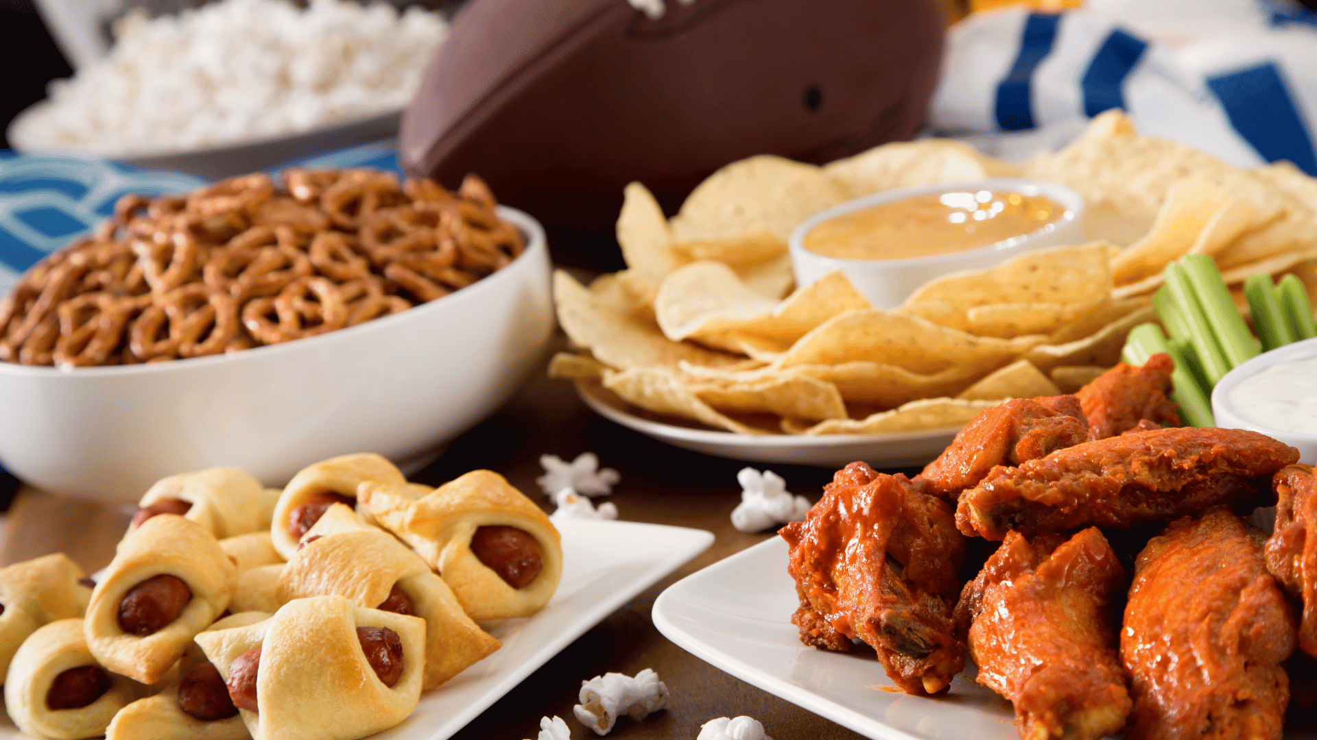Table full of wings, nachos, and dips set for a game day Mealmento